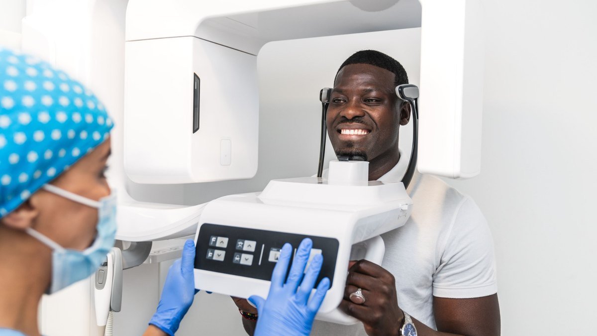 A panoramic dental x-ray reviewed on screen in Orlando Patient positioned in a panoramic x-ray machine while the assistant sets the exposure