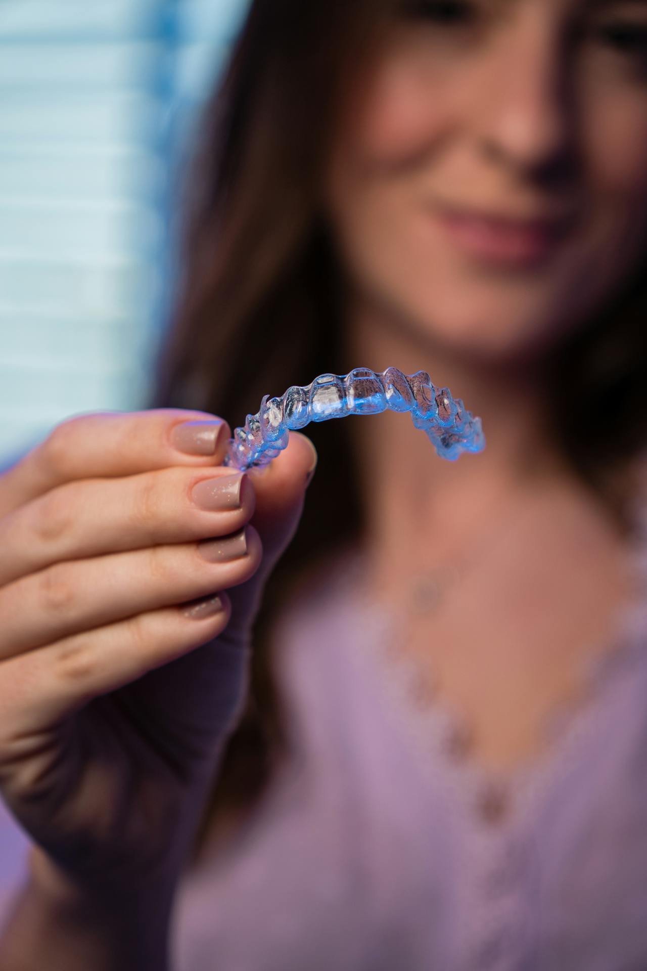 A bright smile holding a clear aligner